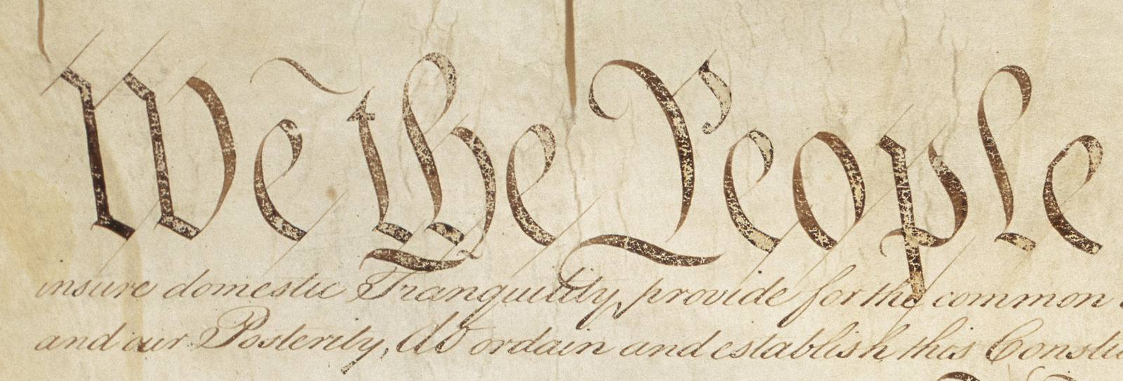 We the People, in large engrossed script, with the ends of two lines of the preamble below it.