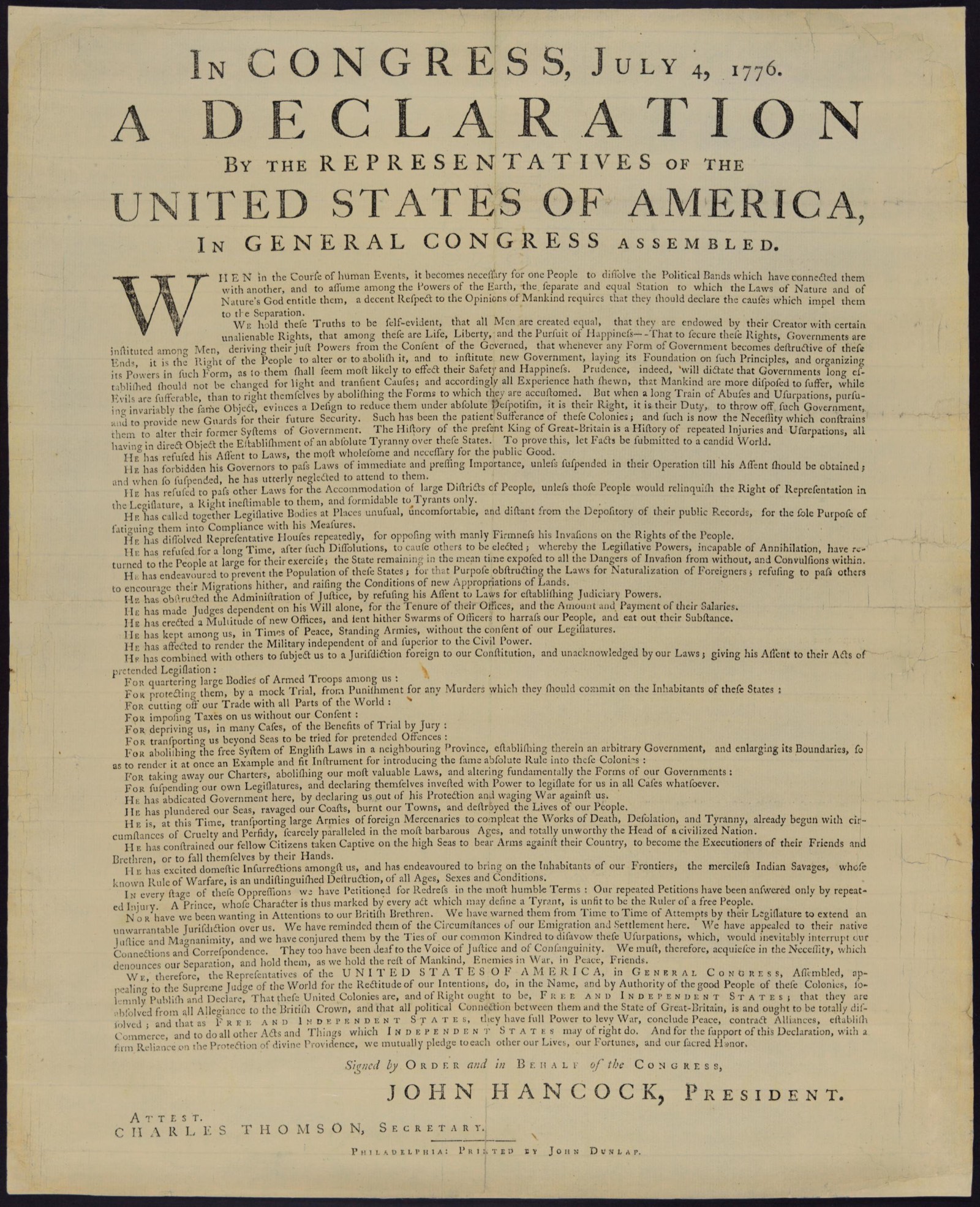 A single printed sheet, yellowed, on a dark ground. The heading runs across the top in large capitals, In Congress, July 4, 1776, A Declaration, with United States of America largest. Below it the text runs down the sheet in small type, a large ornamental W opening the first word. John Hancock, President, is printed above the attestation of Charles Thomson, Secretary, and the imprint at the foot reads Philadelphia: Printed by John Dunlap.